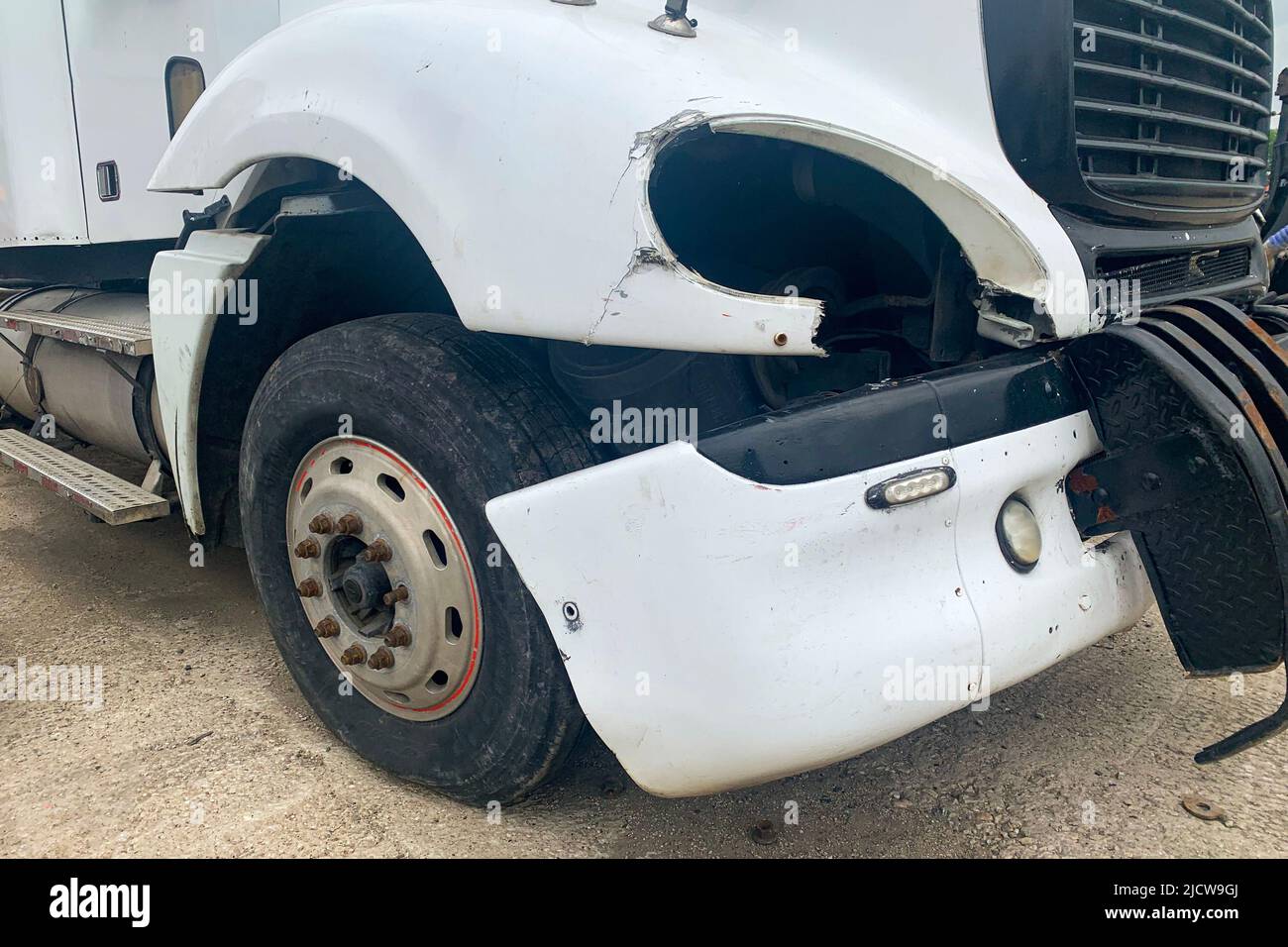 Closeup of abandoned crashed lorry after road accident on a car dump, decay on the front bumper of an white truck without headlight Stock Photo
