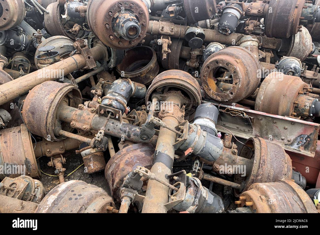 Pile of old rusty truck axle for reusing, used automotive part for sale, old rear differential of truck, car rear axle on junk yard Stock Photo