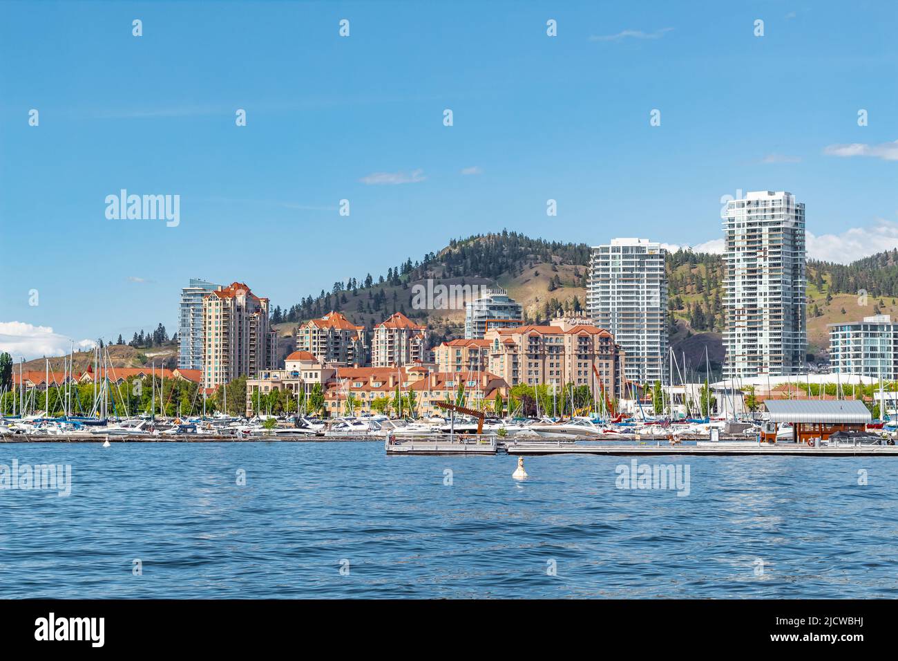 A view of the Kelowna Skyline and Okanagan Lake British Columbia Canada in the summer. Cityscape on sunny summer day. Kelowna Boardwalk. Travel photo, Stock Photo