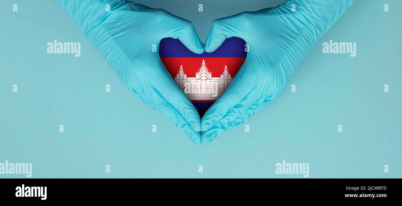 Doctors hands wearing blue surgical gloves making hear shape symbol with cambodia flag Stock