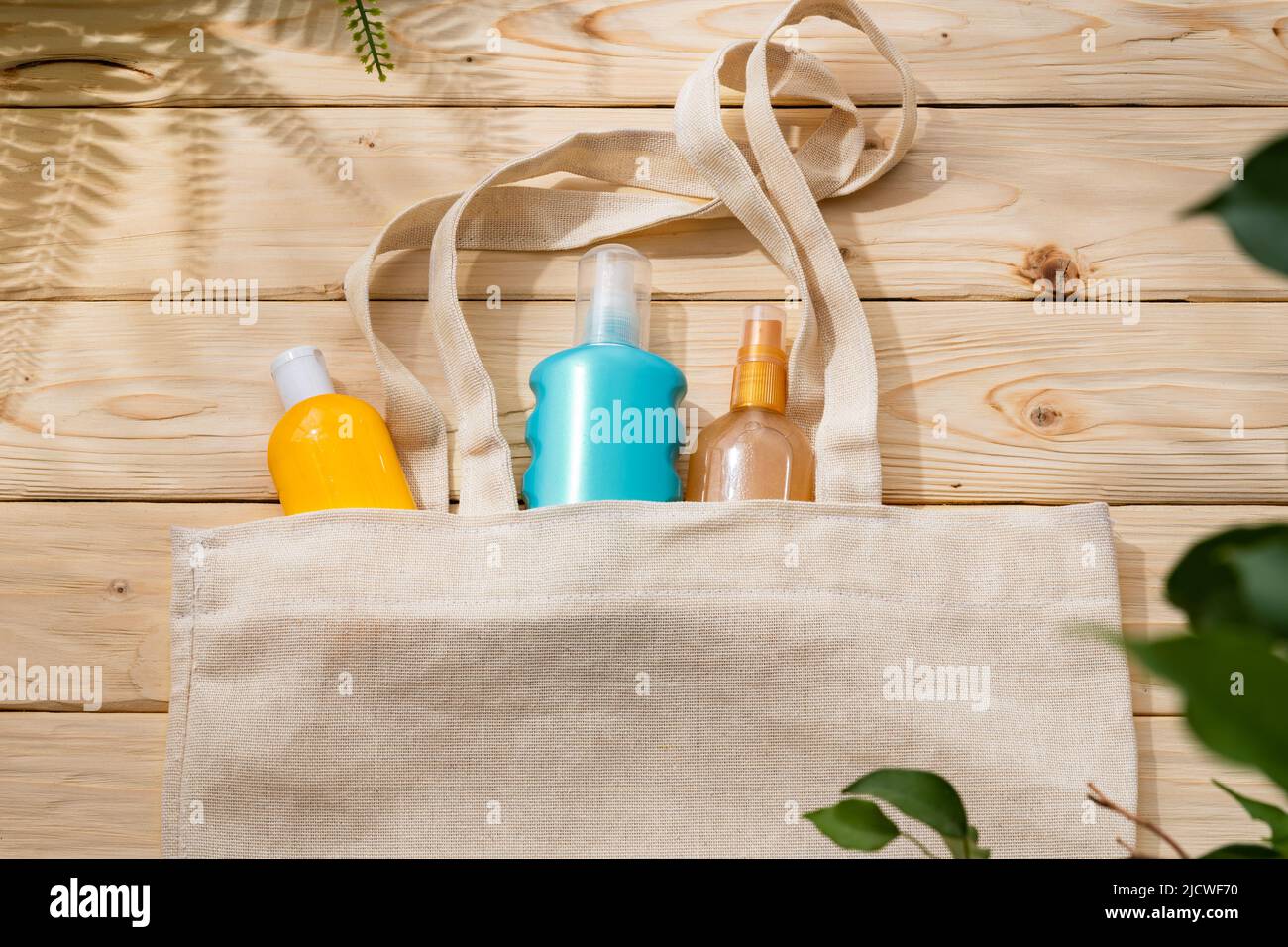 Sunscreen cream bottles in beach bag on wooden background Stock Photo