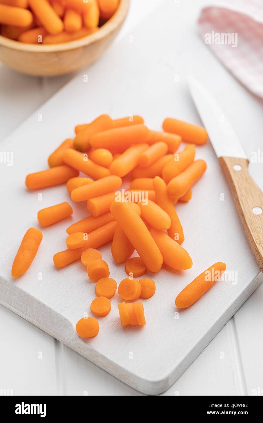 Baby carrot vegetable. Mini orange carrots on white table. Stock Photo