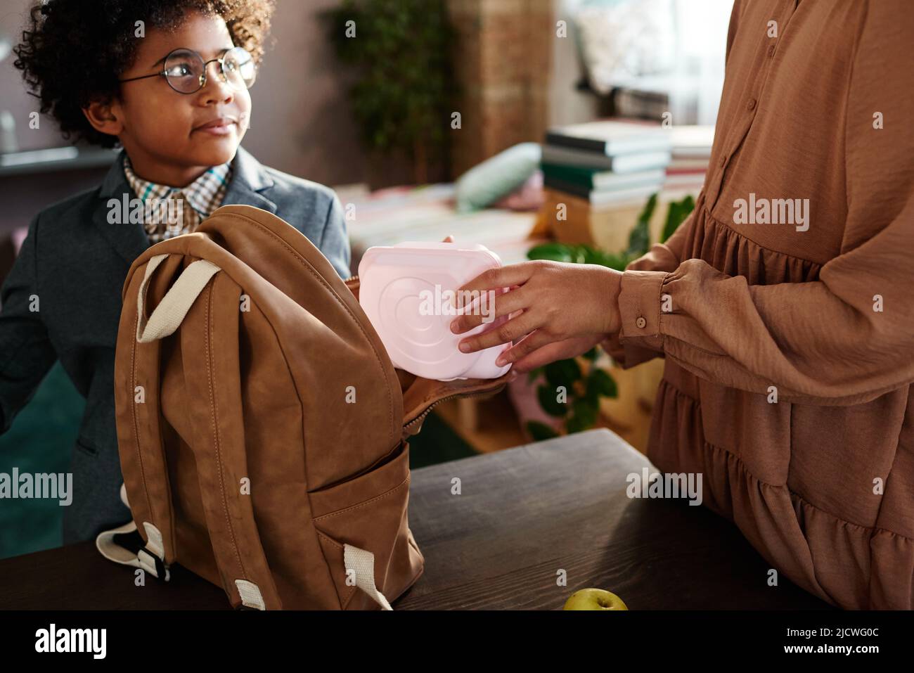 Close-up of girl packing lunch box in school bag for her little brother to send him to school Stock Photo