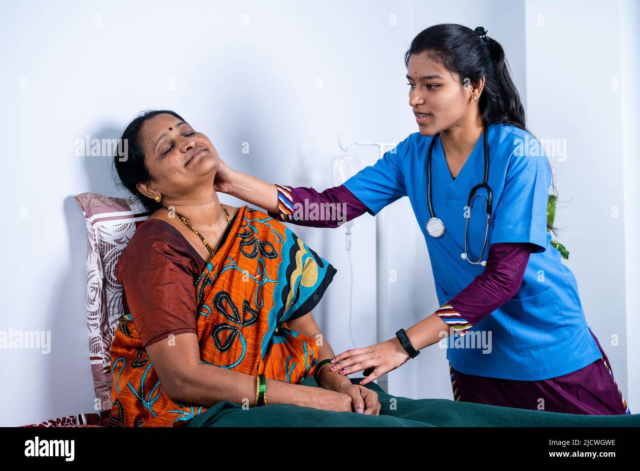 Nurse helping sick senior on bed to do exercise at home - concept of caretaker, assistance and rehabilitation Stock Photo