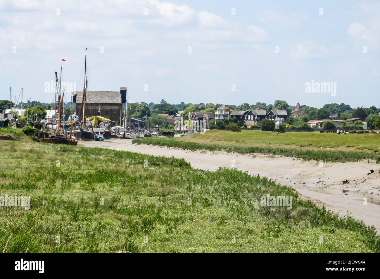 Looking along a dry tidal channel at low tide, towards the dockyard and the town of Faversham in the background Stock Photo