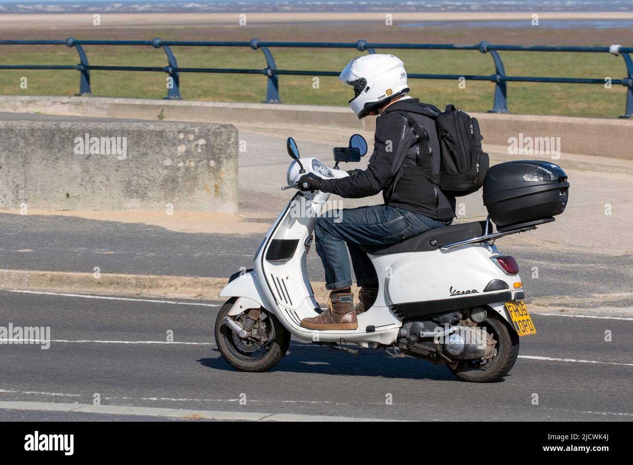 2005 white Piaggio Vespa Scooter dirivng on the seafroint promenade in Southport, UK Stock Photo