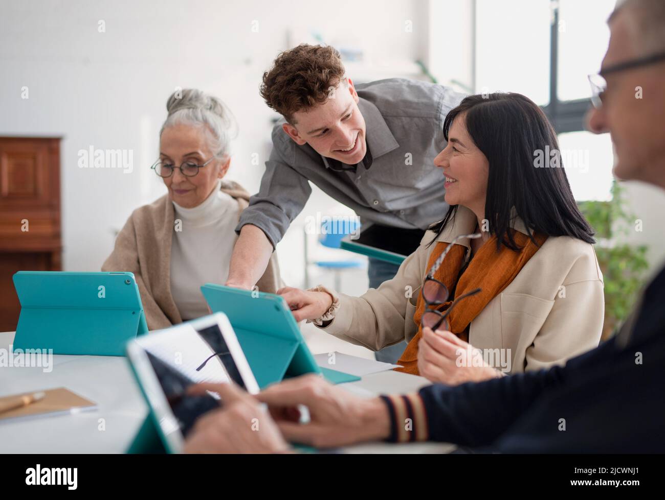Group of seniors attending IT class in community centre with teacher Stock Photo