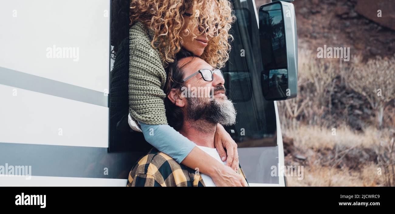 Travel with vehicle concept lifestyle with happy couple in love hugging at destination. Woman hug man with beard. Nature in background. Van camper veh Stock Photo