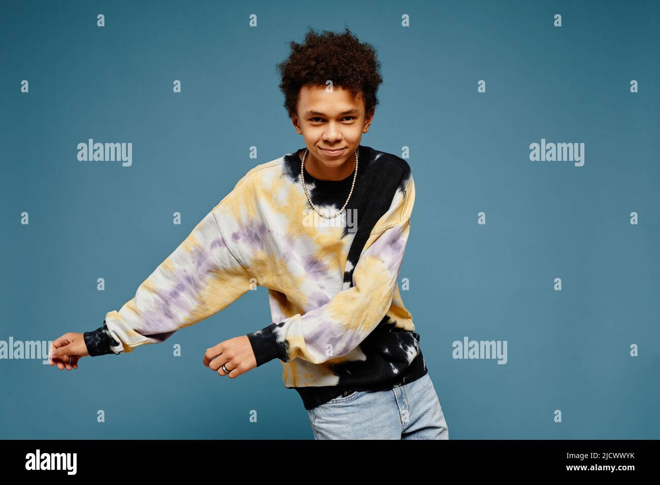 Minimal portrait of black teenage boy wearing tie dye shirt and dancing
