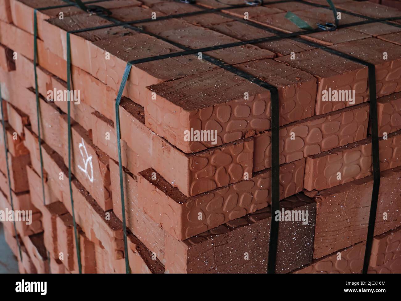 Red building bricks stacked on an outdoor warehouse. Material delivered