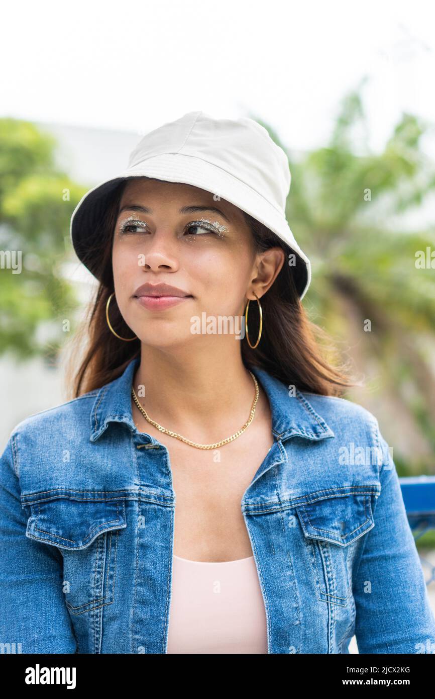 woman in her 20s standing outside with a calm expression, looking to the side. Stock Photo