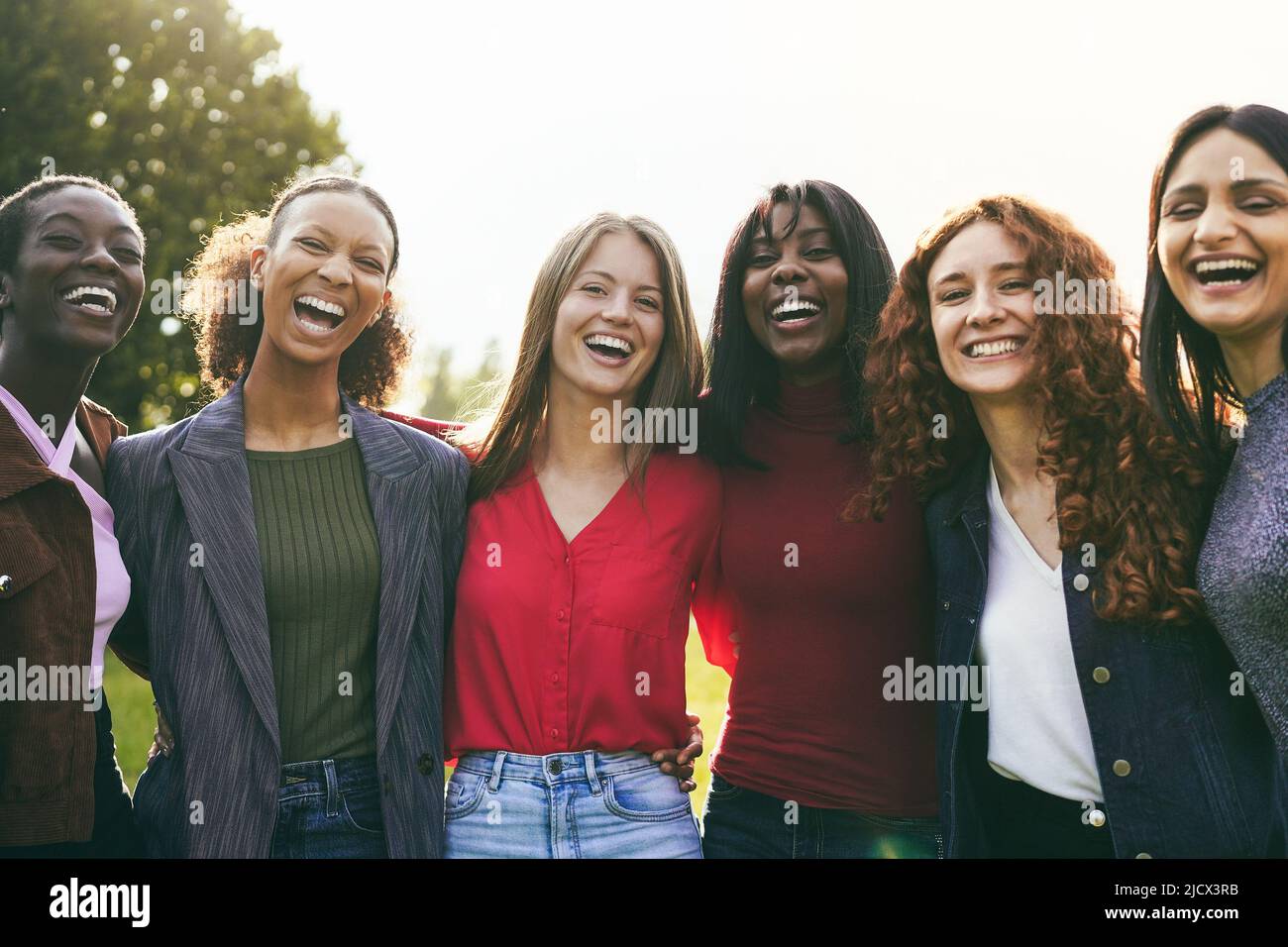 Multiracial female friends having fun hugging together outdoor - Focus ...