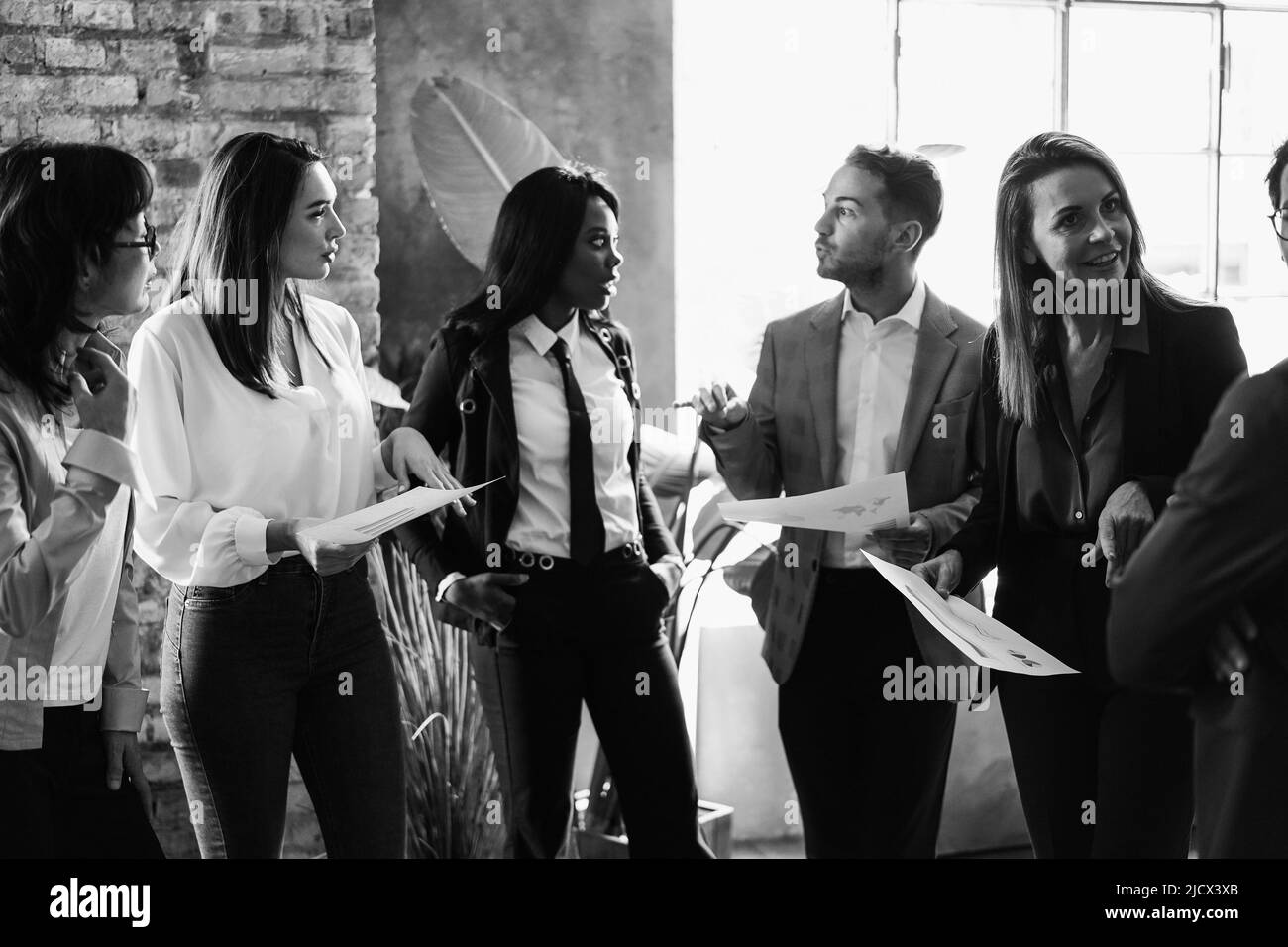 Multiracial business people working inside office - Focus on right senior woman face - Black and white editing Stock Photo