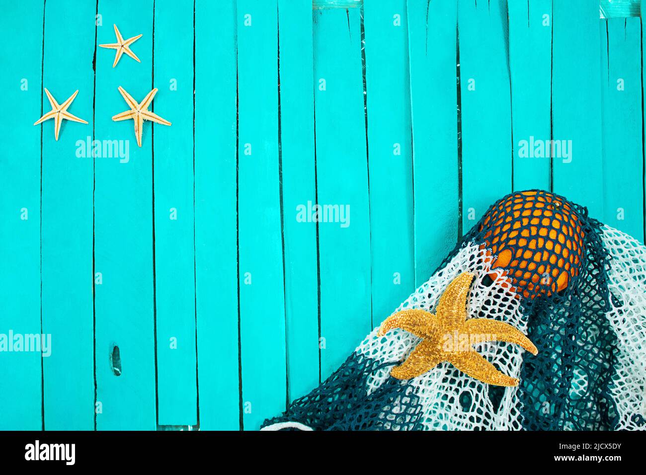 Starfish with bag and orange lie on blue boards. Concept of beach, recreation. Copy space Stock Photo