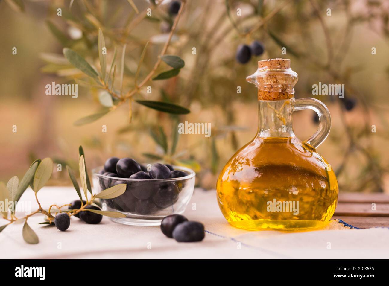 olive oil in a glass bottle and green olives on the background of olive ...