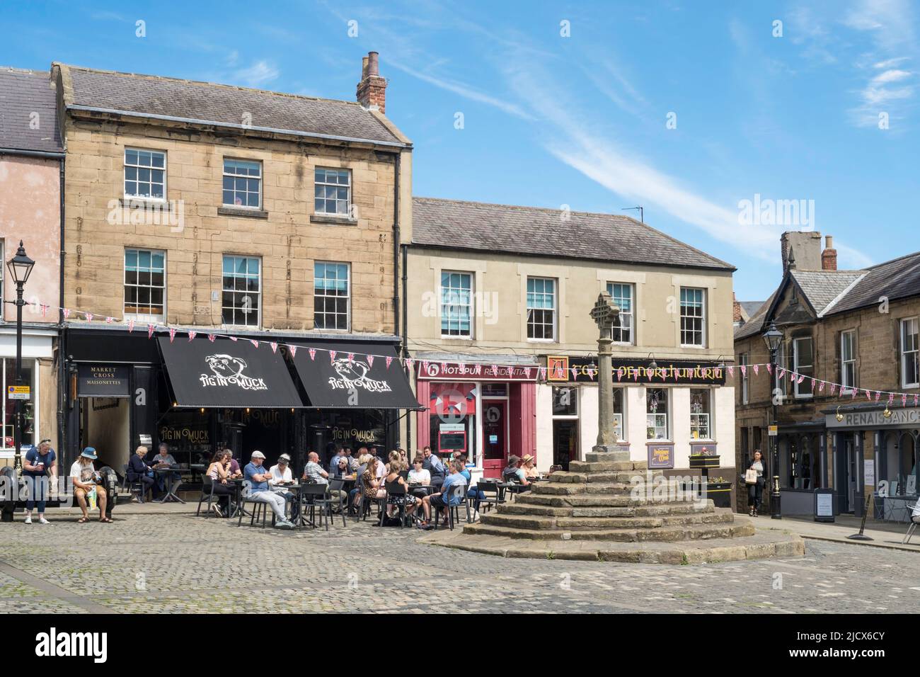 People sitting outside a café in Alnwick Market Square, Northumberland, England, UK Stock Photo