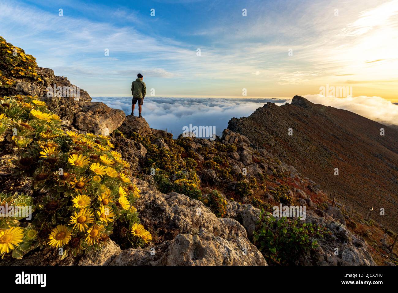 Man watching the mist at sunrise standing on rocks on Pico de la Zarza mountain peak, Fuerteventura, Canary Islands, Spain, Atlantic, Europe Stock Photo