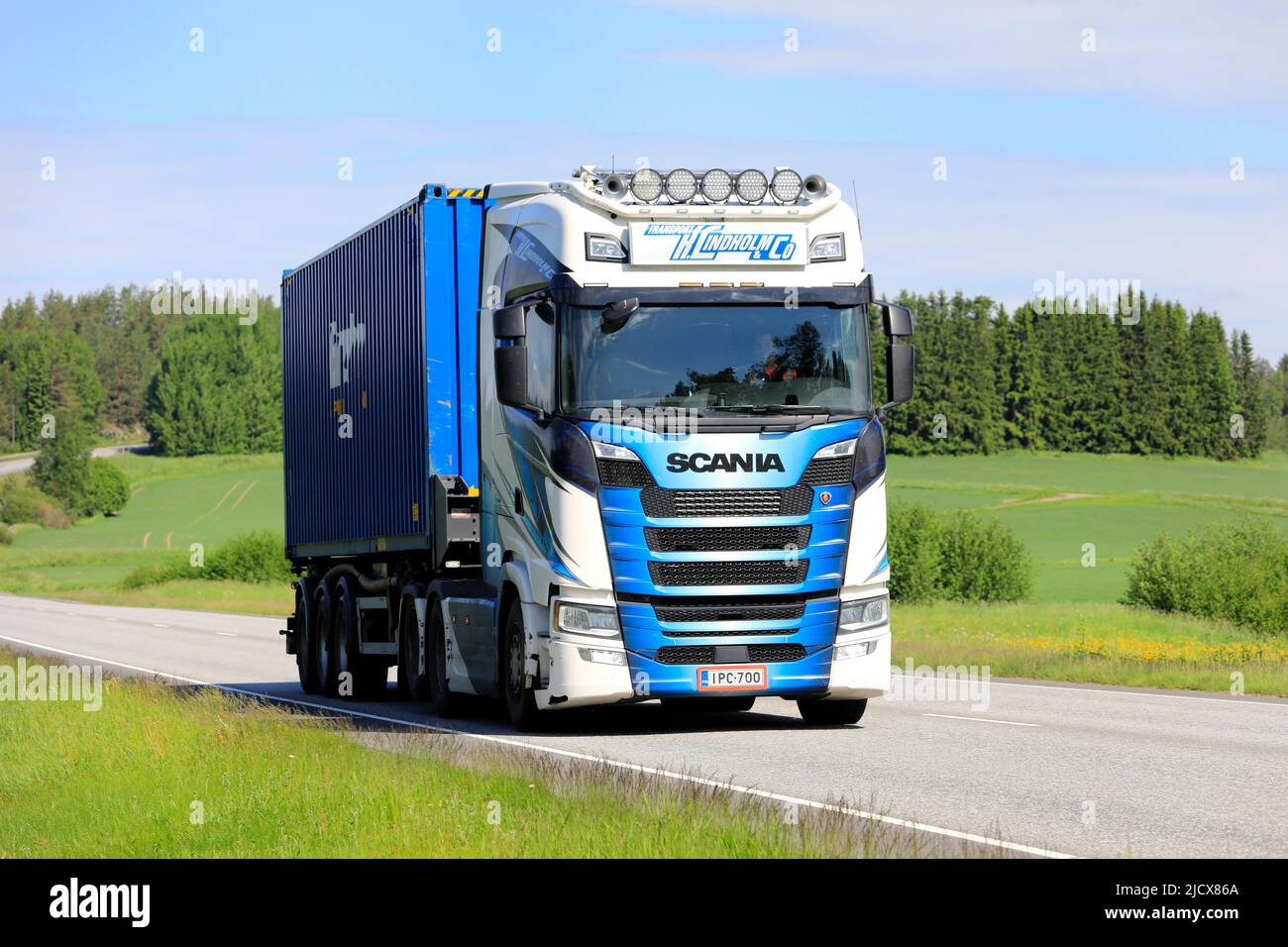 Customised Scania truck of Transport K. Lindholm & Co transports sea container along highway in the summer in Finland. Salo, Finland. June 9, 2022. Stock Photo