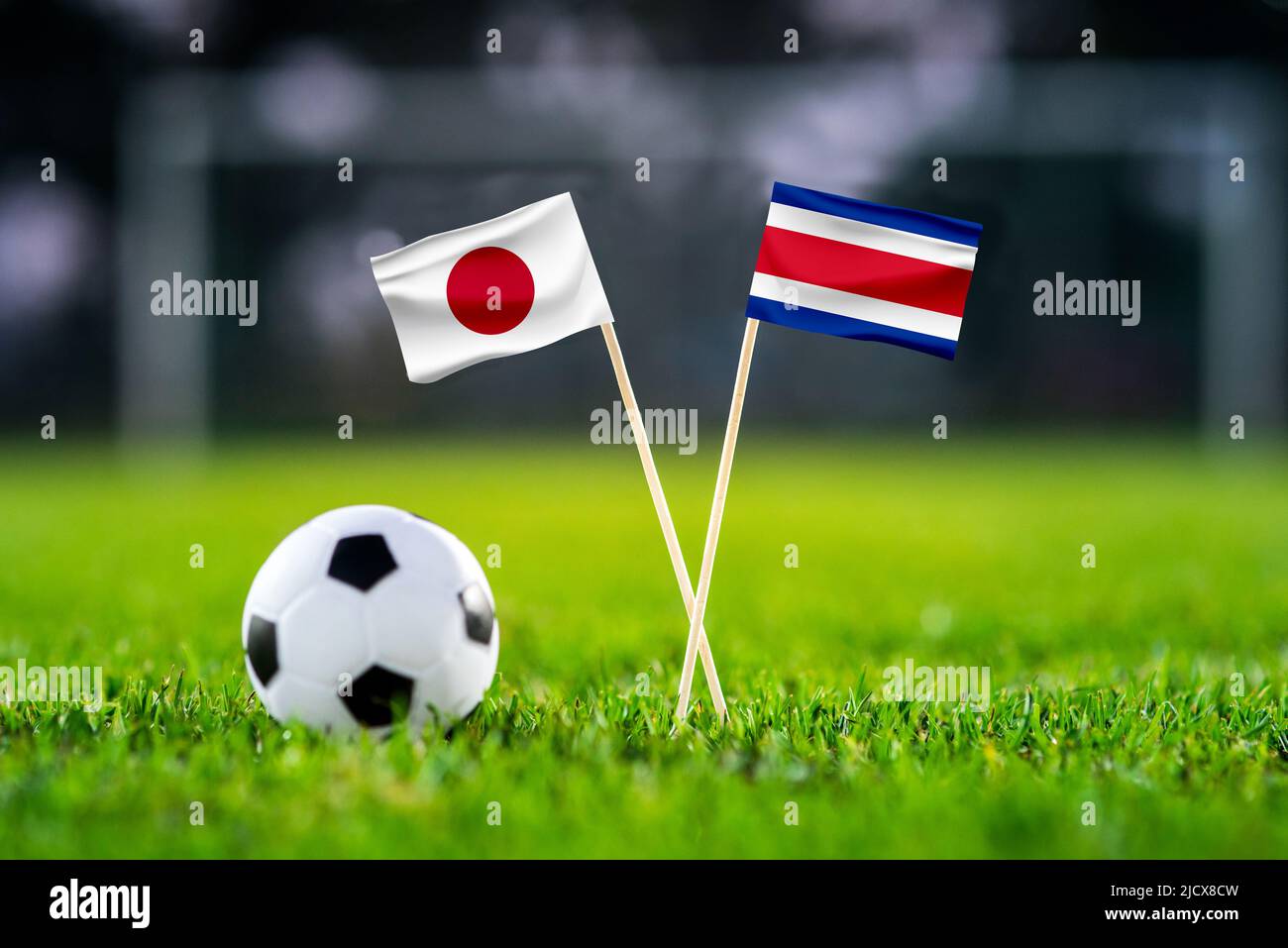 October 2022: Japan vs Costa Rica, Ahmed bin Ali Stadium, Football match wallpaper, Handmade national flags and soccer ball on green grass. Football s Stock Photo