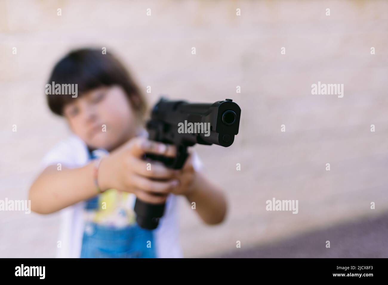 Little girl pointing a gun. Concept of violence, weapons, guns