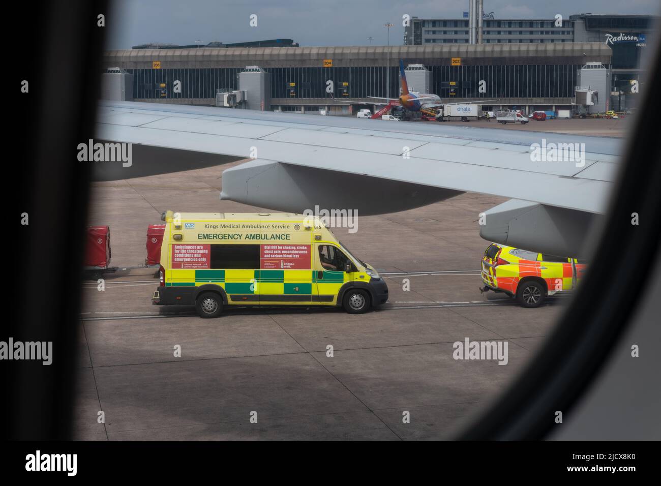 Private medical repatriation ambulance waiting on runway next to plane to collect ill passenger - Manchester Airport, England, UK Stock Photo