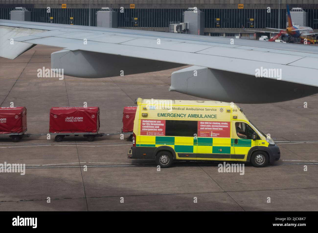 Private medical repatriation ambulance waiting on runway next to plane to collect ill passenger - Manchester Airport, England, UK Stock Photo