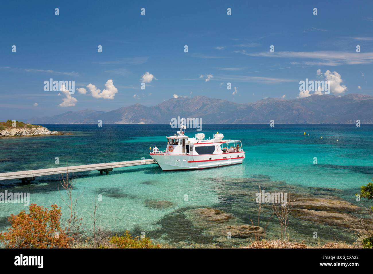 Excursion boat moored at jetty in clear turquoise water off the Plage du Loto, St-Florent, Haute-Corse, Corsica, France, Mediterranean, Europe Stock Photo