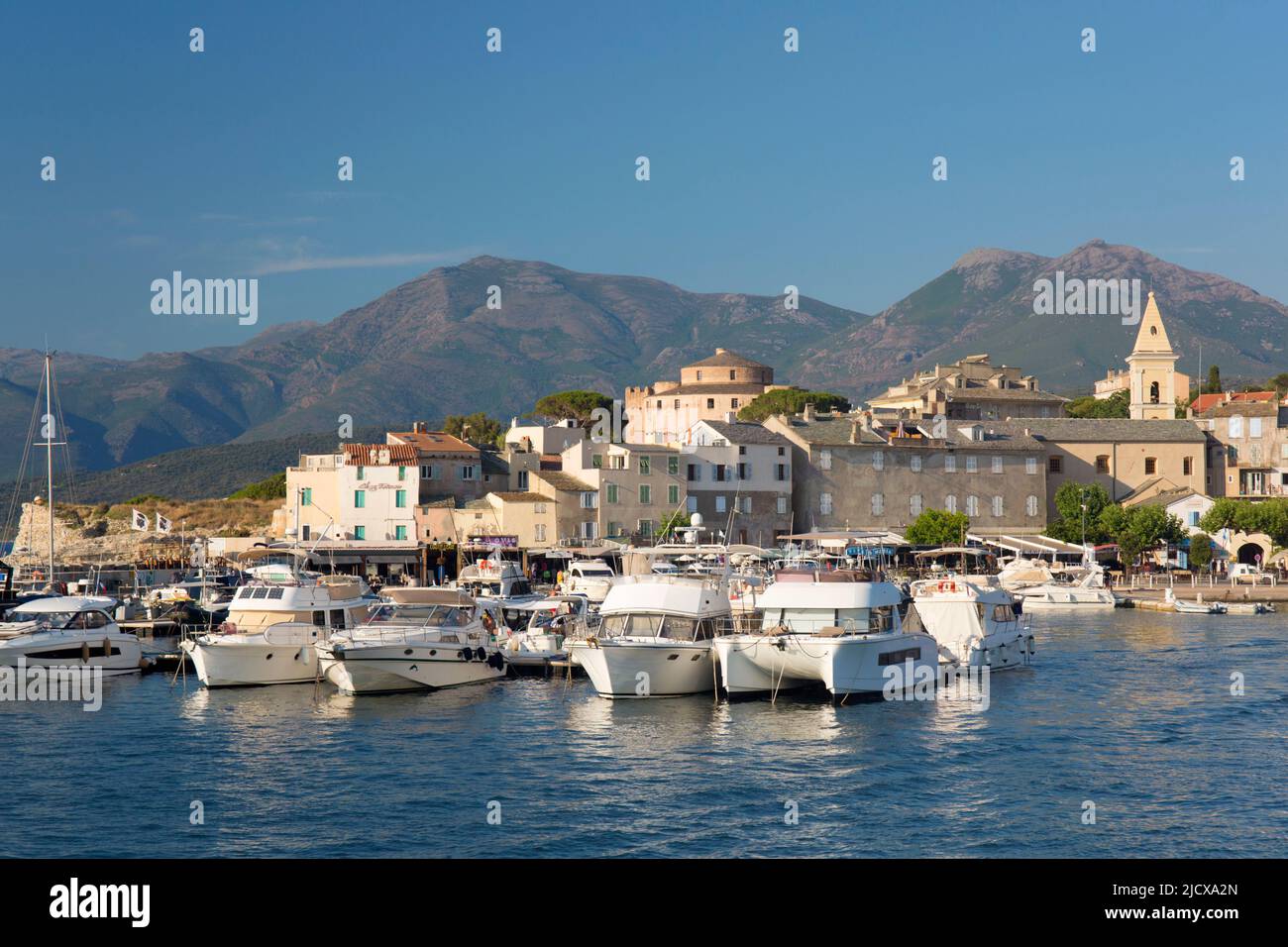 View across harbour to the town and citadel, hills of the Cap Corse peninsula beyond, St-Florent, Haute-Corse, Corsica, France, Mediterranean, Europe Stock Photo