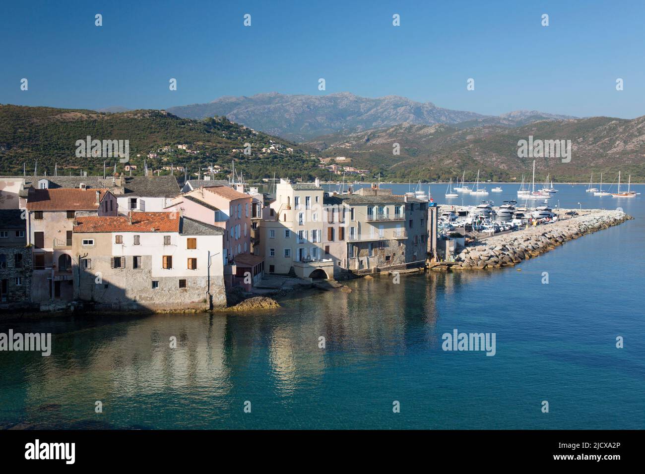 View over rooftops from the citadel ramparts, waterside houses reflected in calm sea, St-Florent, Haute-Corse, Corsica, France, Mediterranean, Europe Stock Photo