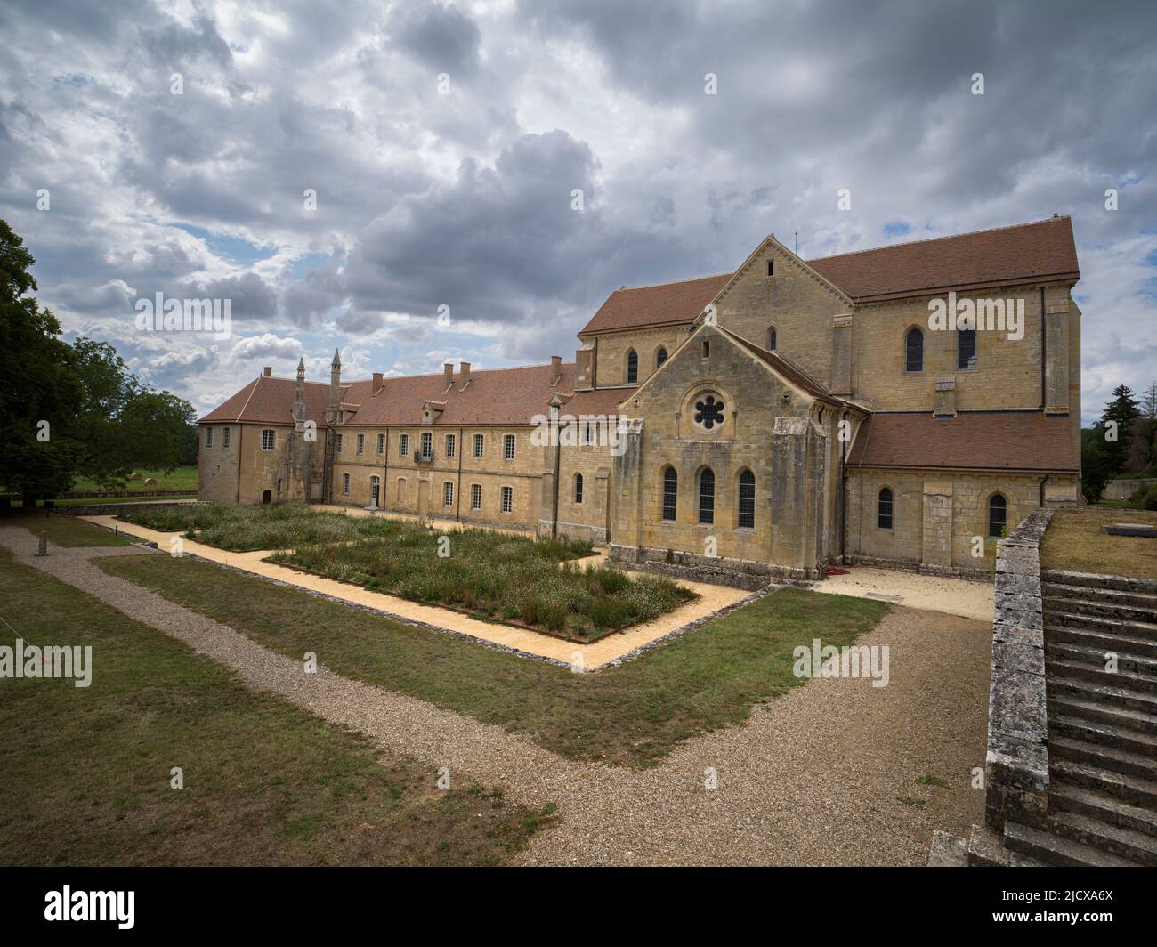 Garden and the exterior of the ancient Noirlac Abbey on a cloudy day, Cher, Centre-Val de Loire, France, Europe Stock Photo