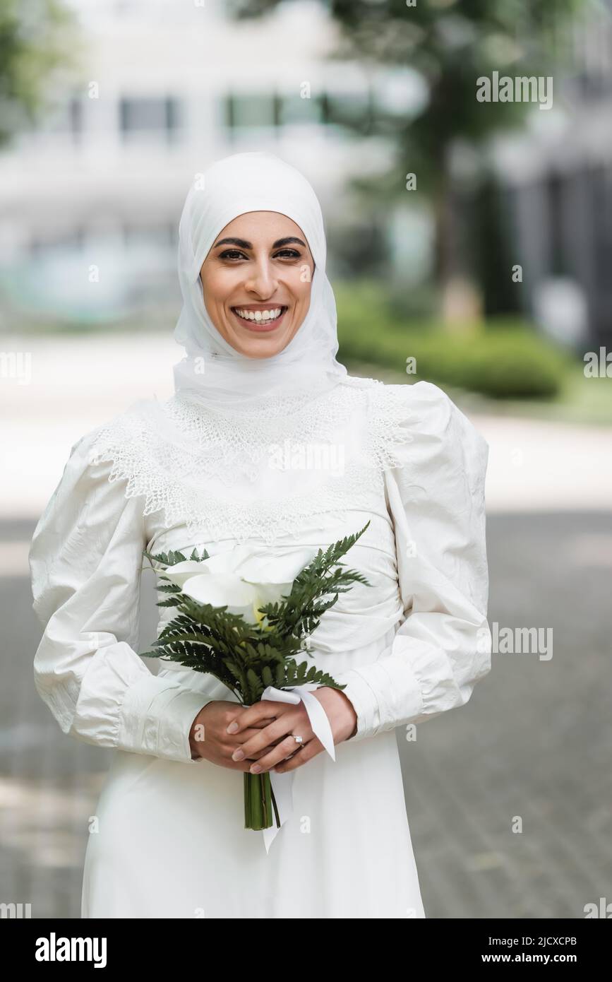 happy muslim bride with diamond ring on finger holding wedding bouquet