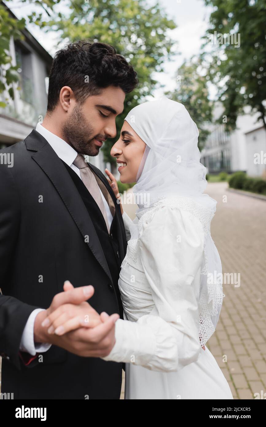 happy muslim bride and groom with closed eyes holding hands Stock Photo