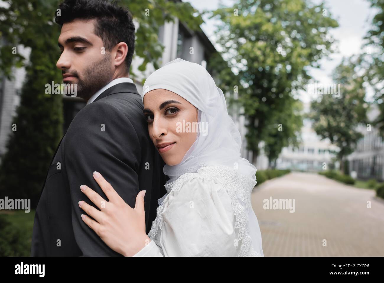 muslim bride in hijab and wedding dress hugging groom Stock Photo