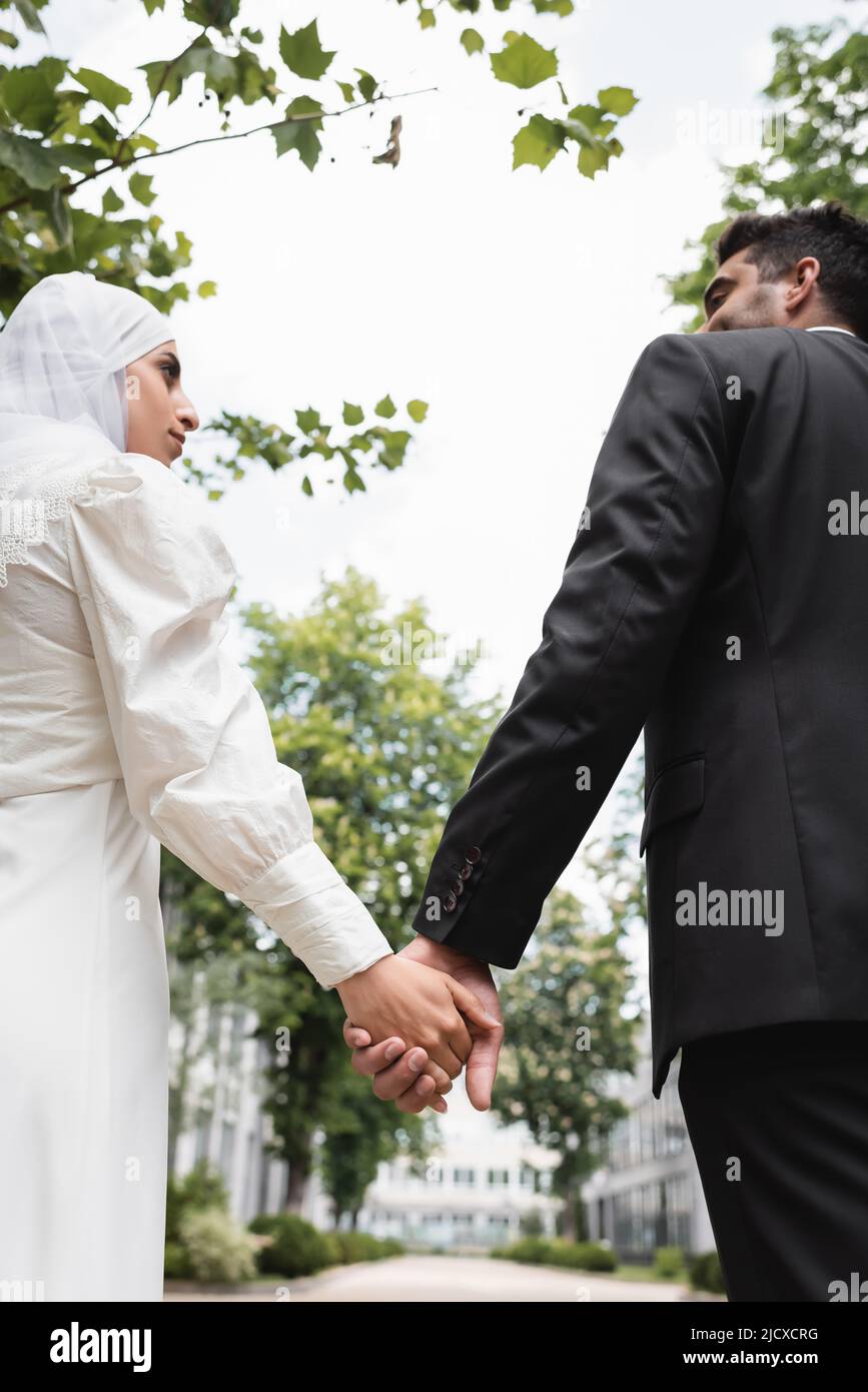 low angle view of groom and muslim bride holding hands Stock Photo