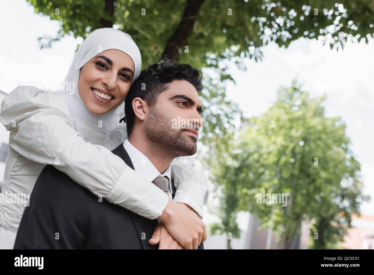 pleased bride in hijab hugging muslim groom in suit Stock Photo Alamy