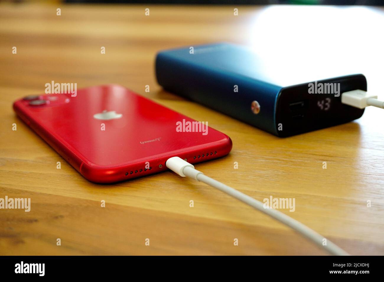 30 April 2021 Eskisehir Turkey. Red iphone 11 being charged by powerbank on wooden table Stock Photo