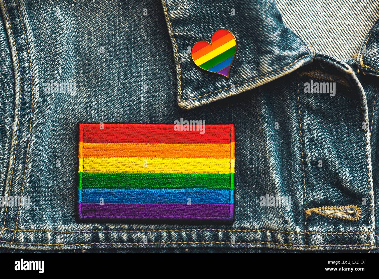 Close-up of LGTBI flag textile patch on a denim jacket and LGTBI pin heart shaped. Pride day concept Stock Photo