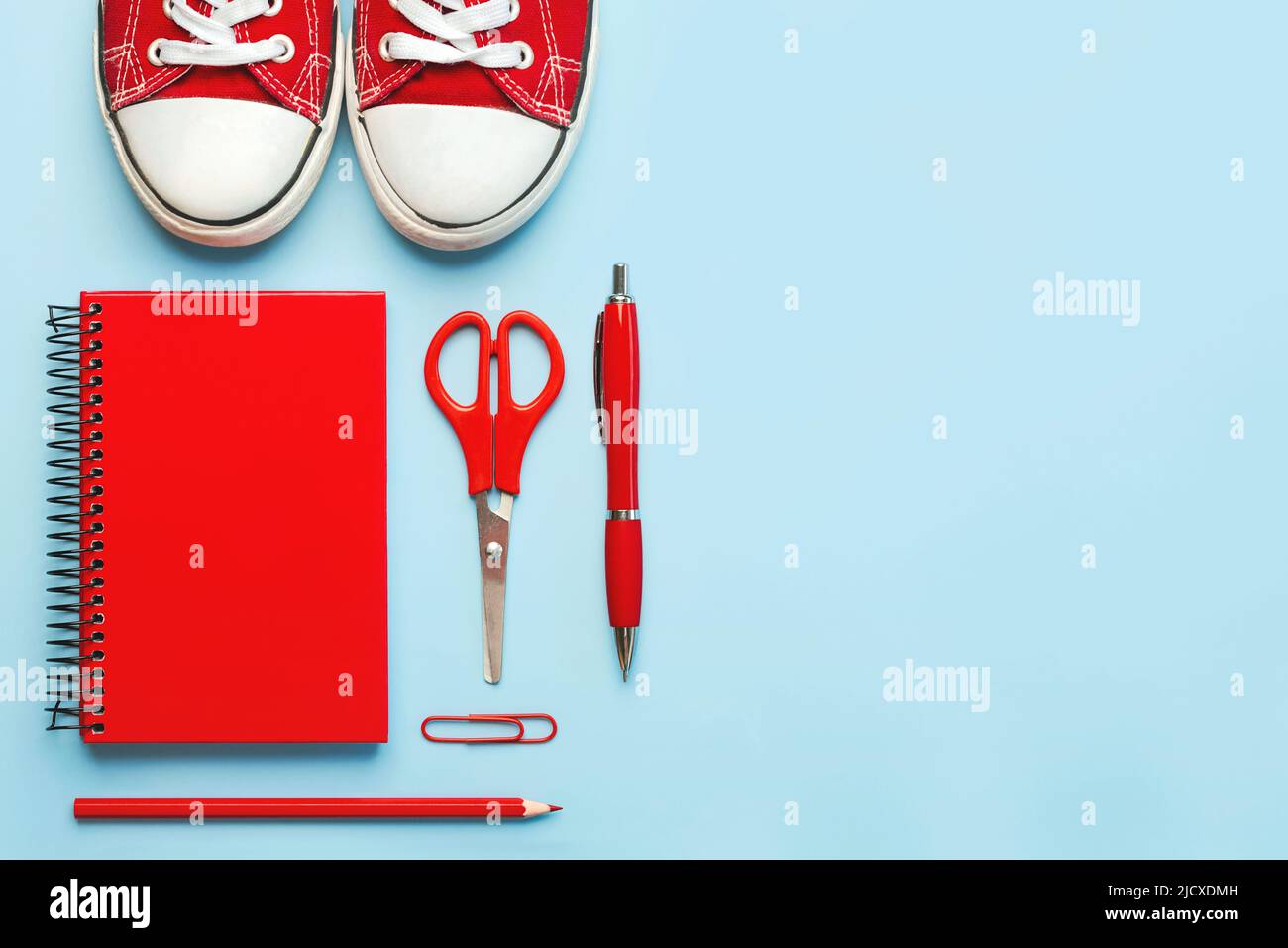 Top view of red sneakers and red school supplies with space for tex on blue background. Back to school concept Stock Photo