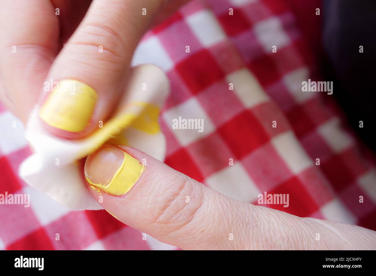 Woman removing nail polish on red table cloth background close up view Stock Photo