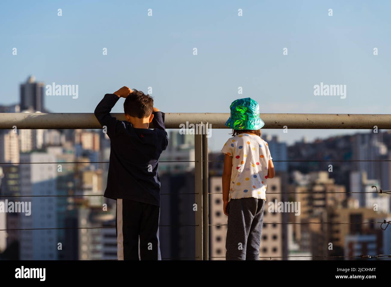 Rear view of a boy and a girl on the deck of Parque Amilcar Vianna Martins looking at the high rise buildings in Belo Horizonte, Minas Gerais, Brazil. Stock Photo