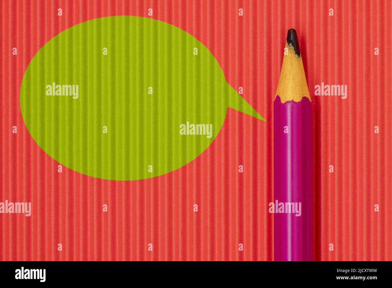 Purple pencil on red paper background with green speech bubble Stock Photo