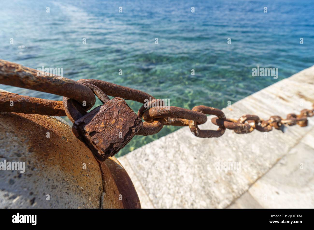 A rusted chain and an old rusty lock on a boardwalk Stock Photo