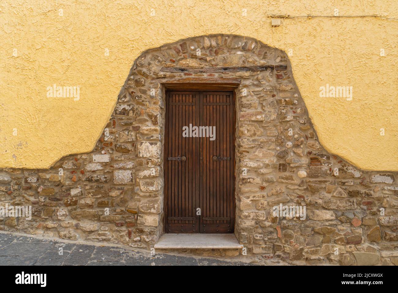 A partially plastered stone wall with a door in the middle Stock Photo