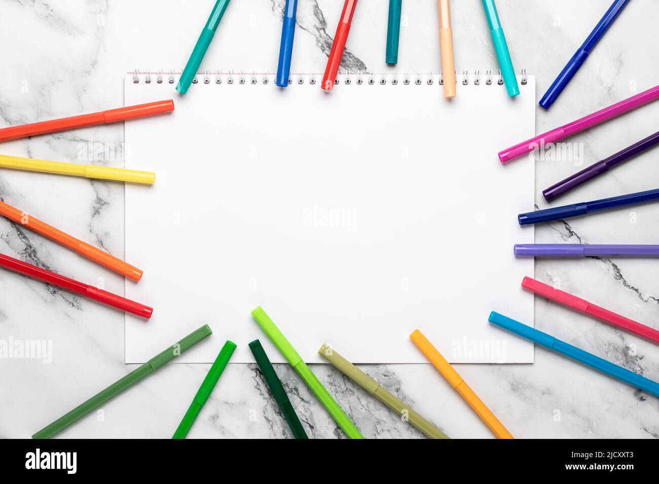 Background with pencils and white blank paper, felt pens frame. Open sketchbook. Mockup, template. Colored markers for drawing on a marble desk. Flat Stock Photo