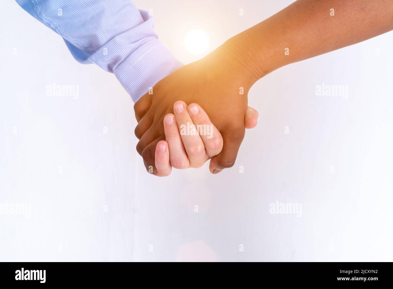 The candid photo of the arms of a white boy hugging the arms of a black teenage girl. Handshake of children. Candid couple. No face. First teenage you Stock Photo
