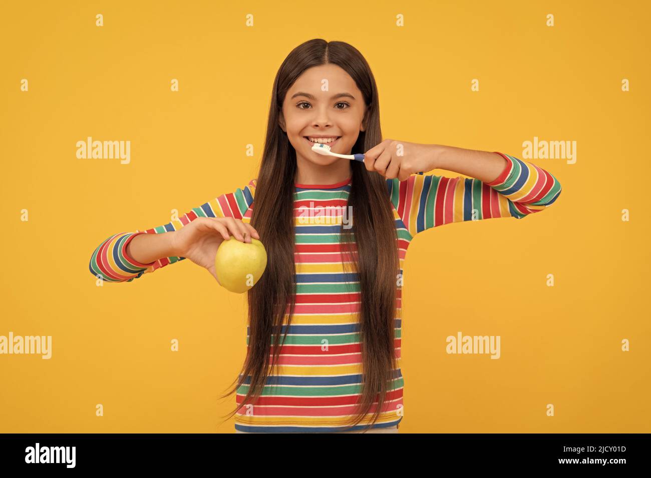 Brush teeth twice daily. Happy child brush teeth holding apple. Oral