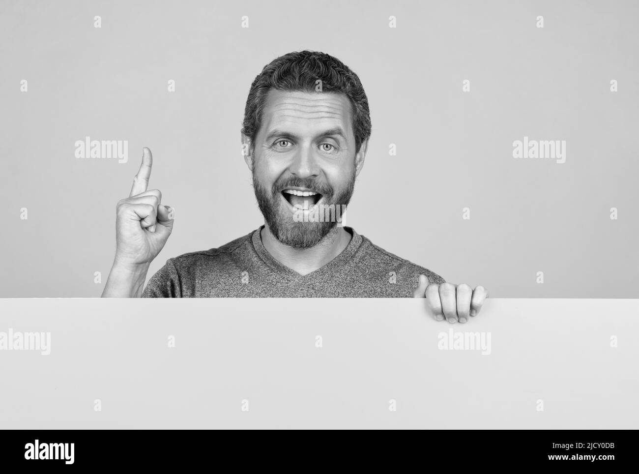 happy bearded man raised finger inspired with idea behind yellow paper for copy space, advertisement Stock Photo