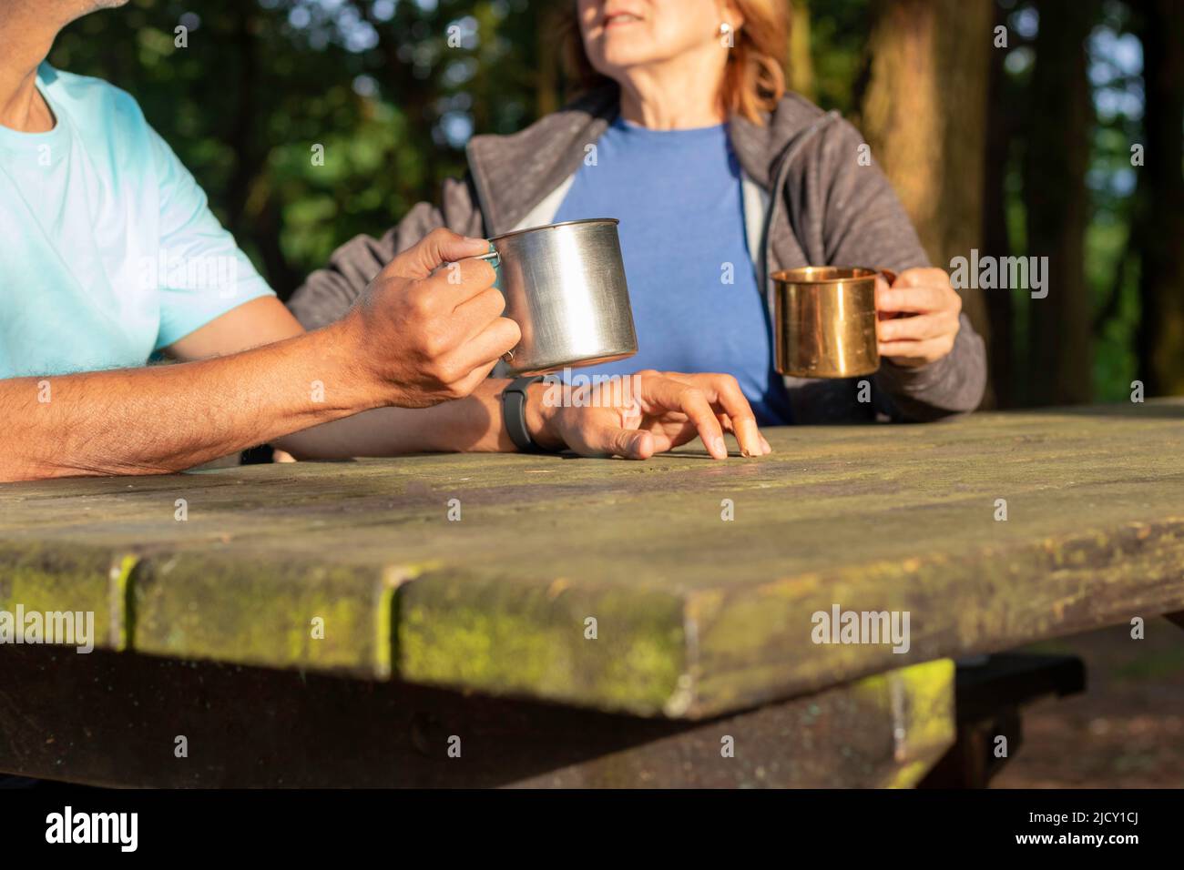 Unrecognizable senior couple holding and drinking from metal cups on a