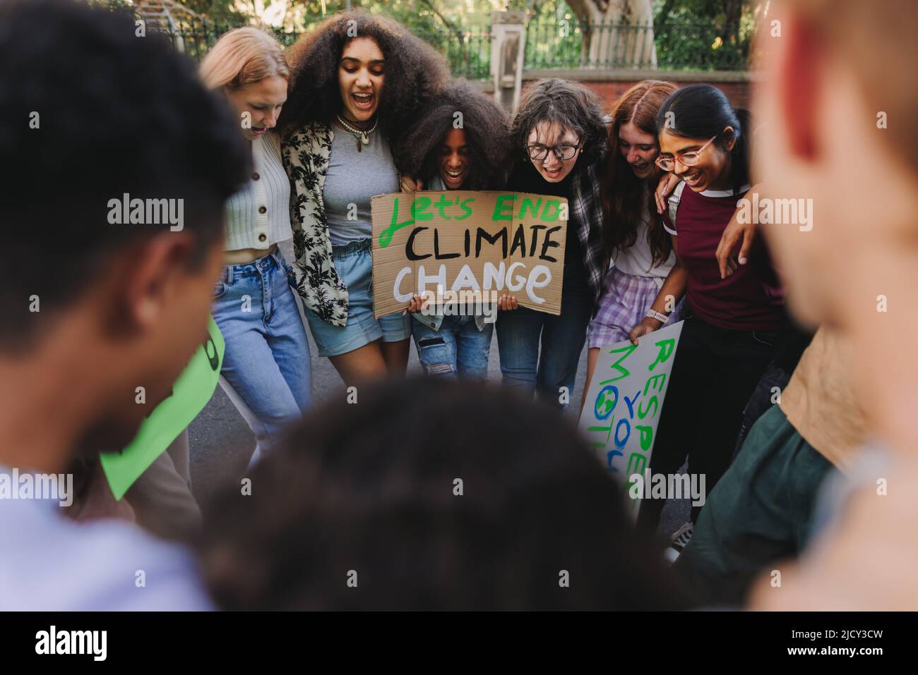 Group of diverse young people standing together in a circle at a climate change demonstration. Multicultural youth activists joining the global climat Stock Photo