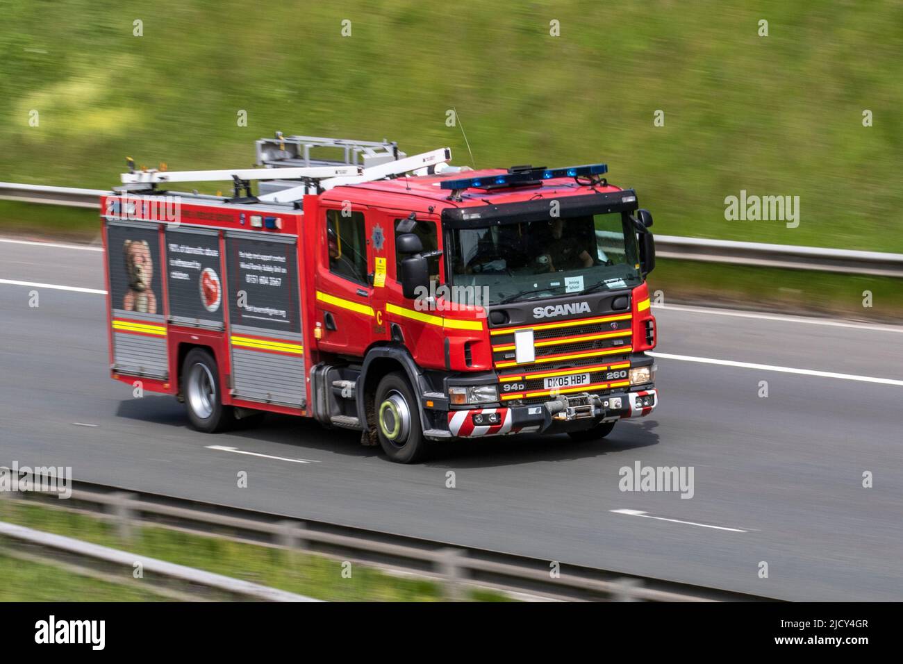 Emergency Fire and Rescue appliance responding to incident, travelling at speed with blue lights flashing on the M6 Motorway, UK Stock Photo